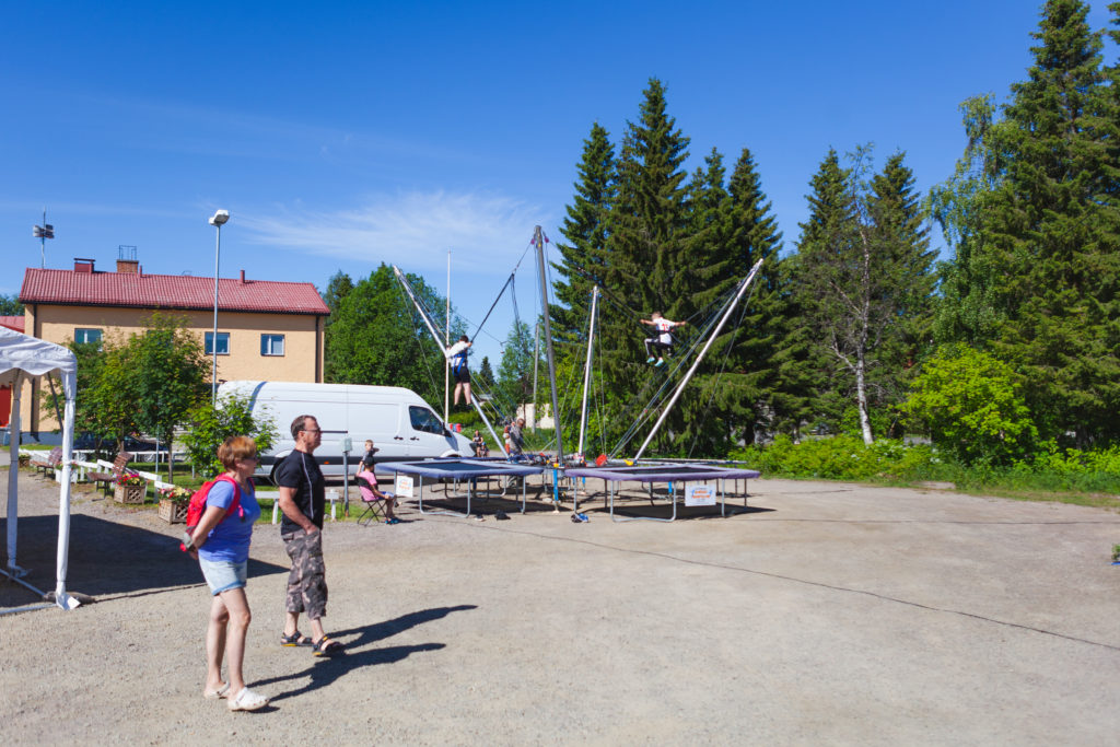Kaksi lasta pomppii valjaiden varassa kumpikin omilla trampoliineilla.